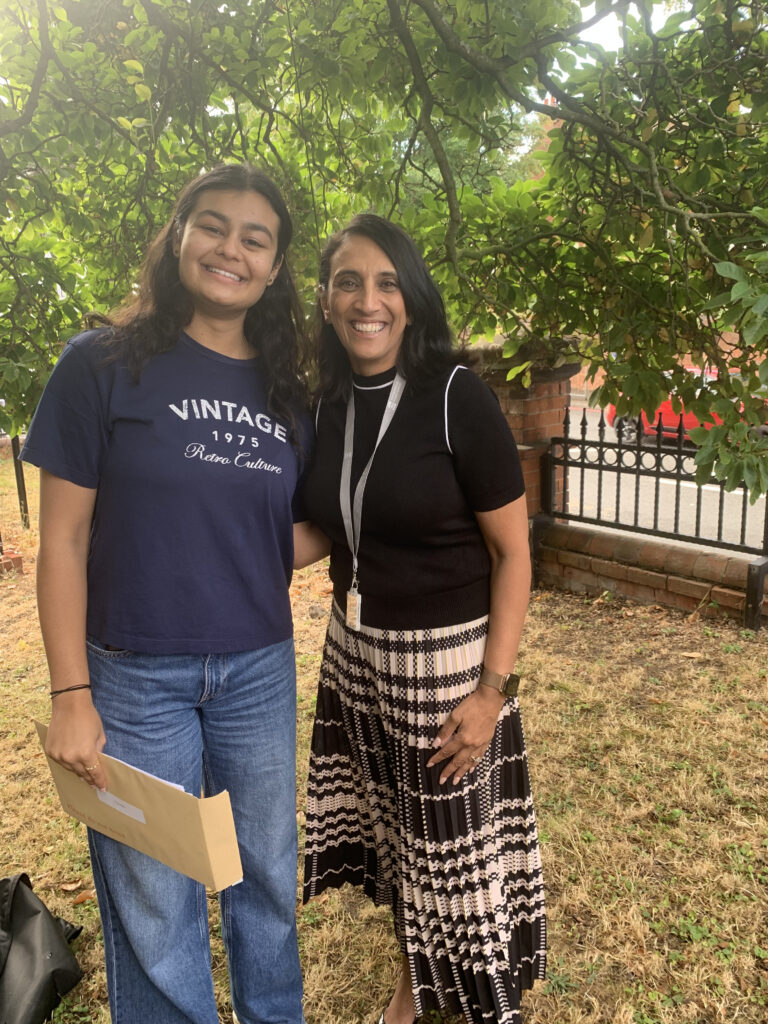 Headteacher of Hydesville Tower School Raj Samra stands smiling posing for a photo with pupil who is smiling after opening her GCSE results
